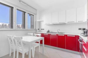 eine Küche mit roten Schränken sowie einem weißen Tisch und Stühlen in der Unterkunft Santa Giulia Suite - Futurismo 17 in Mailand