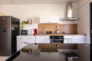 eine Küche mit weißen Schränken und einem schwarzen Kühlschrank in der Unterkunft Le Séquoia - Maison neuve climatisée in Saix