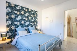 a bedroom with a blue bed with a floral accent wall at Le Séquoia - Maison neuve climatisée in Saix