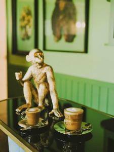 una estatua de mono sentada en una mesa con dos tazas de café en Hotel Eco Boutique Bidasoa, en Santiago