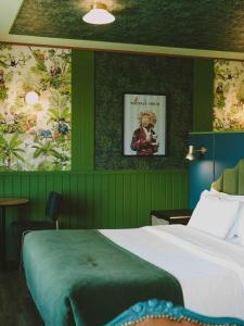 a bedroom with green walls with a bed and a painting at Hotel Eco Boutique Bidasoa in Santiago