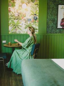 una mujer sentada en una mesa en una habitación verde en Hotel Eco Boutique Bidasoa, en Santiago