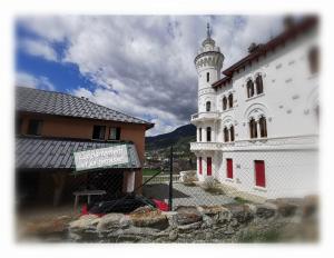 a large white building with a tower on top of it at Duplex avec piscine et sauna in Jausiers