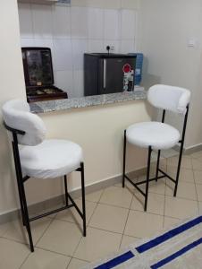 dos taburetes blancos sentados en un mostrador en un salón en Casa Gem, en Nairobi