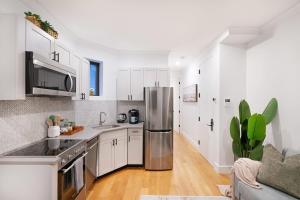 cocina con armarios blancos y nevera de acero inoxidable en 1288-3RS New Renovated 2 Bedrooms, en Nueva York