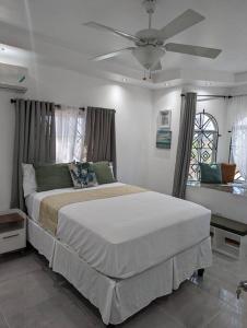 a bedroom with a large bed with a ceiling fan at The Chateau Guesthouse- Old Harbour in Old Harbour