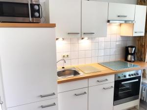 eine Küche mit weißen Schränken und einer Spüle und einer Mikrowelle in der Unterkunft 3-Sterne Komfortferienwohnung  Köhnke 6 - [#122261] in Goslar