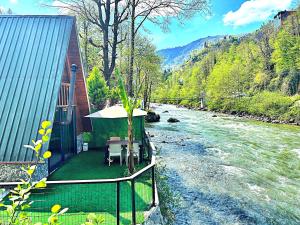 a house with a table and chairs next to a river at Tabiat Bungalows in Çamlıhemşin