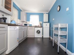 a kitchen with blue walls and a washer and dryer at Flat 1 Niles Place in Padstow +12 photos