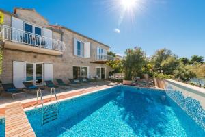 a swimming pool in front of a villa at Luxury Beachfront Villa Casa Mare with private heated pool and gym right at the beach in Mirca - Brac in Supetar