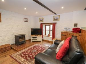 a living room with a leather couch and a fireplace at Graig Las The Barn in Oswestry