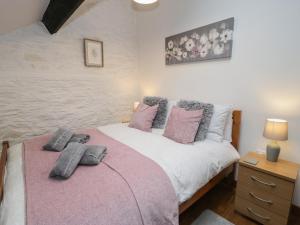 1 dormitorio con 1 cama con almohadas rosas y grises en Graig Las The Barn en Oswestry