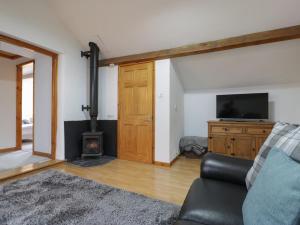 a living room with a couch and a tv and a fireplace at Graig Las The Stables in Oswestry