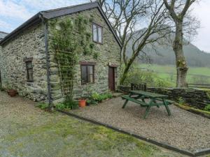 a stone house with a picnic table in front of it at Graig Las The Stables in Oswestry