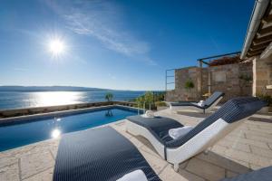 a swimming pool with two lounge chairs next to a house at Luxury Villa Murvica with private pool near the beach in Murvica on Brac island in Murvica