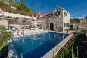 a villa with a swimming pool in front of a house at Luxury Villa Murvica with private pool near the beach in Murvica on Brac island in Murvica