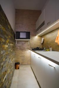 a kitchen with white cabinets and a stone wall at Todor Apartmani in Kladovo