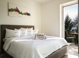 a bedroom with a large white bed with a window at SalvatoreHomes - Luxury Villa with private Garden & BBQ in San Zeno di Montagna