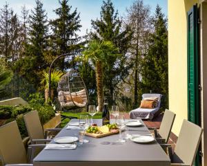 einen Tisch mit Weingläsern und einen Obstteller auf der Terrasse in der Unterkunft SalvatoreHomes - Luxury Villa with private Garden & BBQ in San Zeno di Montagna