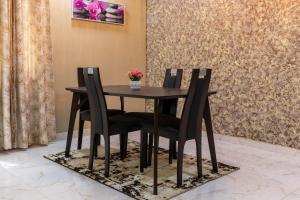 a black dining room table and chairs with flowers on a rug at THE OPULENT OASIS in Accra