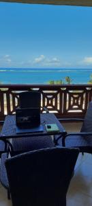 La Mera Beachfront Apartment في مومباسا: يوجد جهاز كمبيوتر محمول على طاولة في الشرفة