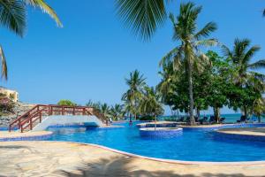 una piscina con palmeras en la playa en La Mera Beachfront Apartment en Mombasa
