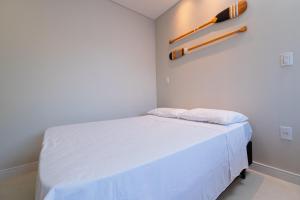ein kleines Schlafzimmer mit einem weißen Bett und einem Baseballschläger an der Wand in der Unterkunft Pousada Kauai SFS in São Francisco do Sul