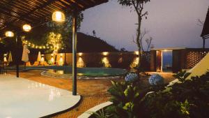 eine Terrasse mit einem Pool in der Nacht mit Lichtern in der Unterkunft Bản Nhỏ - Little Village in Cao Bằng