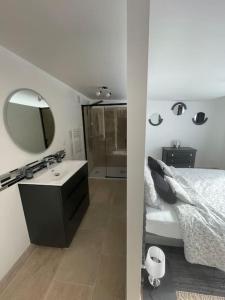 ein Bad mit einem Bett, einem Waschbecken und einem Spiegel in der Unterkunft Le Catalpa, gite avec piscine et jacuzi privés in Lestiou