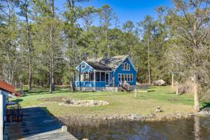 a blue house sitting on the side of a lake at Dog-Friendly Westover Cottage with River Access! in Marion