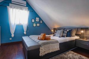 Un dormitorio con una cama con paredes azules y una ventana en Duplex Bonbon Coco en San Pedro