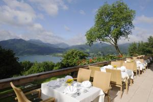 um restaurante com mesas e cadeiras brancas e vista para um lago em Berghaus - Der Westerhof Hotel em Tegernsee