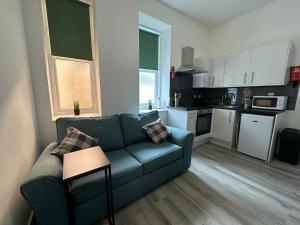 een woonkamer met een bank en een keuken bij Carmen Sylva Llandudno Beach ground floor Flat in Llandudno