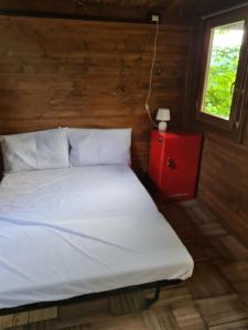 a bed in a room with a red table and a window at Ecochiocciola in Montese