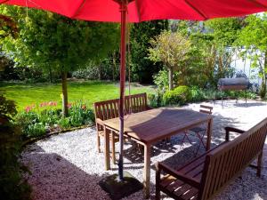 a wooden table with an umbrella in a garden at Campen Cottage in Krummhörn