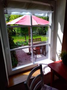 an open window with an umbrella on a patio at Campen Cottage in Krummhörn