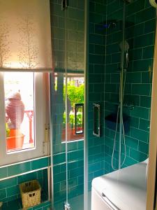uma casa de banho em azulejos azuis com um chuveiro e uma janela em Loft independiente FORGET ME NOT em Getxo