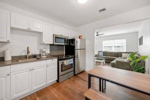 德爾雷比奇的住宿－Sunny Gem, Steps to Atlantic Ave，厨房以及带白色橱柜和沙发的客厅。
