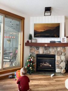 a baby standing in a living room with a fireplace at TOP FLOOR at very Base of Hill w AC & Best Views on Mountain in Panorama