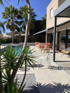 a patio with a white chair and palm trees at Villa de luxe vue mer et piscine privée casa de Palma à Torrox Costa in Torrox Costa