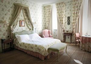 a bedroom with a large bed and a chair at La Chartreuse Du Val Saint Esprit in Gosnay