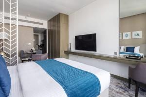 ein Hotelzimmer mit einem Bett und einem Flachbild-TV in der Unterkunft Frank Porter - Prive A in Dubai