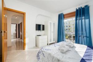 a bedroom with a bed with blue curtains and a television at Blife Allya private rooms in Faro