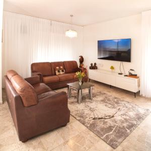 Exclusive Jerusalem Villa في Giv‘ot Mordekhay: غرفة معيشة مع أريكة بنية وطاولة
