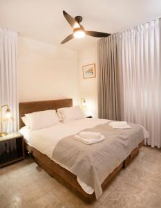 Exclusive Jerusalem Villa في Giv‘ot Mordekhay: غرفة نوم بسرير كبير مع مروحة سقف