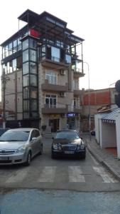 dois carros estacionados num parque de estacionamento em frente a um edifício em Hotel Italia em Tirana