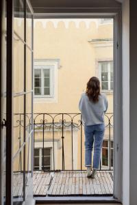 Una mujer parada en un balcón con vistas a una ventana en Marktplatz-Residenz - 110 m vom Traunsee, en Gmunden