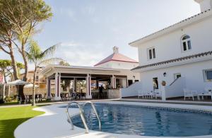 a villa with a swimming pool in front of a house at Hotel Novomar in Chiclana de la Frontera