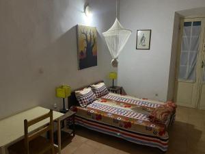 a bedroom with a bed and a table in it at HOTEL DU PALAIS in Saint-Louis