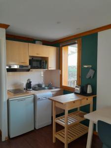 a kitchen with white appliances and a wooden table at T2 confortable - Piscine chauffée - Super Besse in Besse-et-Saint-Anastaise